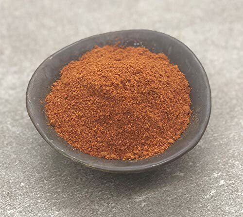 Bowl filled with chili powder on a gray surface.